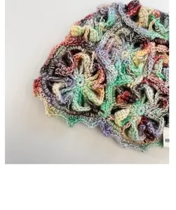 Close-up view of multicolor handmade crocheted hollow knit beanie showing intricate flower details.