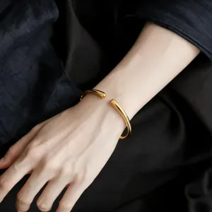 Bracciale rigido aperto dorato minimalista goccia polso dettaglio foto moda accessorio