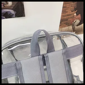 Close-up detail of clear PVC backpack shoulder straps, showing durable grey webbing and transparent design.