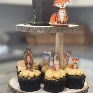 Close-up detail of woodland animal wooden cake toppers on a rustic tiered stand.