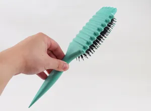 Detail shot of a teal boar bristle hair brush with ergonomic handle and air cushion design.