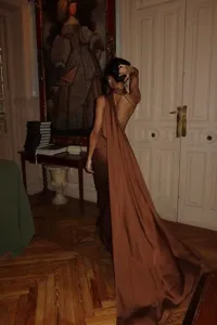 Detalle del elegante vestido largo marrón de satén con halter y una larga cola elegante.