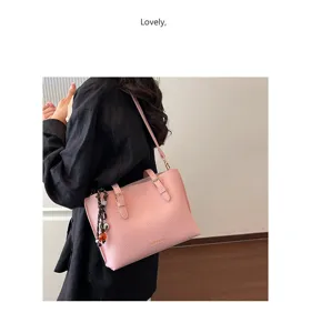 Vista detallada del bolso de cuero rosa, diseño minimalista de trabajo con elegante colgante.