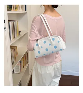 Vista detallada del elegante bolso de boliche blanco con divertidos lunares azules.