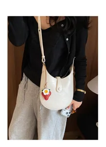 Close-up detail of the stylish white crescent shoulder bag with cute strawberry charm.