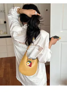 Minimalist yellow saddle shoulder bag for women, chic underarm purse with charm decor.