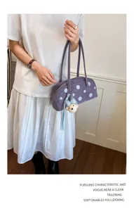 Vista detallada del elegante bolso de hombro de lunares con un bonito colgante de oso.