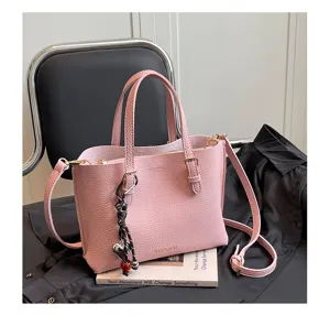 Vista detallada de bolso de mano de cuero rosa para mujer, elegante tote con colgante y asas dobles.