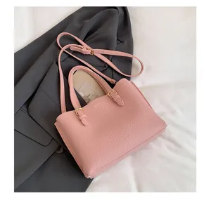 Vista detallada del bolso de mano de cuero rosa con elegantes hebillas doradas y correa duradera.