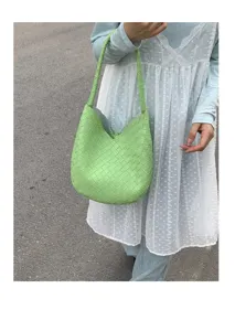 Detail shot of a light green woven shoulder bag, crafted from premium leather with classic pattern.