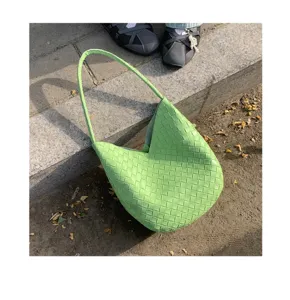 Detailed view of green woven leather shoulder bag, classic intrecciato texture outdoor style.