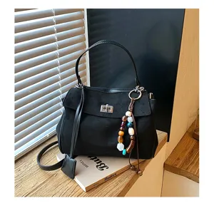 Detailed view of the black suede women handbag showcasing textured material and beaded charm.