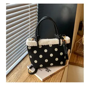 Nahaufnahme einer schwarzen Handtasche mit weißen Punkten, Plüschrand und Lederhenkel.