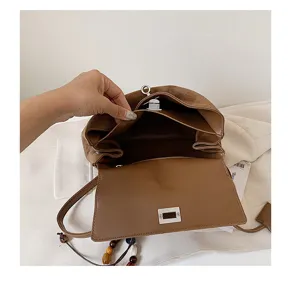 Brown suede handbag interior detail showing multi-compartment structure and turn-lock closure.
