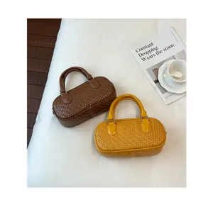 Detail view of woven top handle handbag in brown and yellow, featuring textured faux leather.