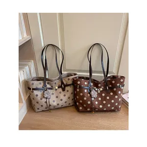 Detail shot of suede polka dot tote bags featuring metallic clasps and cute floral pendants.