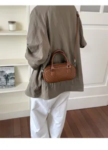 Detail view of a brown woven pattern shoulder bag worn by model, lifestyle indoor setting.