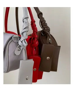 Knotted handle cylindrical shoulder bag detail, women fashion minimalist handbag view.