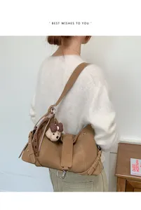 Detailansicht der braunen Retro-Umhängetasche mit süßem Bären-Anhänger und eleganter Schleife.