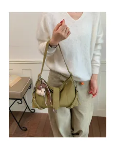 Detailaufnahme der grünen Retro-Achseltasche mit Metallschließe und süßem Plüsch-Hundeanhänger.