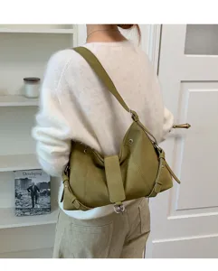 Detailaufnahme der retro grüne Schultertasche mit Schnallenriemen und Metallring-Akzenten.