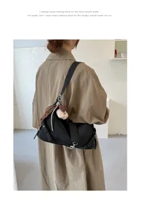 Detailansicht der stilvollen schwarzen Achseltasche mit süßem Plüschbären-Anhänger-Accessoire.
