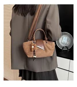 Retro brown suede handbag detail, featuring elegant design and a cute flower charm.