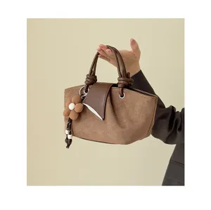 Vintage suede handbag detail showing the soft texture, knotted handle, and cute floral charm.