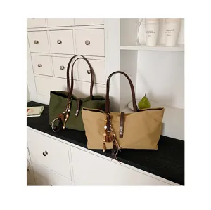 Casual canvas tote bag large capacity shoulder handbag with leather strap and tassel charms detail.