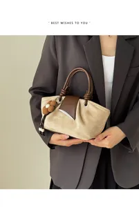Close-up detail of vintage suede handbag featuring brown leather flap and flower pendant.