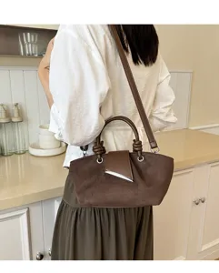 Close-up detail of the brown suede shoulder handbag worn in a chic kitchen setting.
