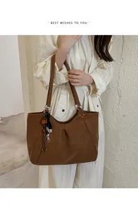 Brown tote bag detail view showing large capacity, soft leather texture, and stylish tassel charm.