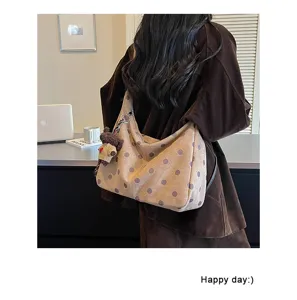 Detail shot of retro polka dot suede hobo shoulder bag with cute bear charm for autumn winter.