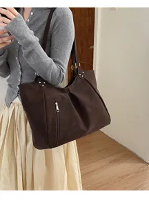 Detailed view of the dark brown slouchy tote bag, showcasing soft texture and front zipper pocket.