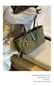 Retro large-capacity canvas shoulder bag for women, versatile minimalist tote with stylish tassel charm.