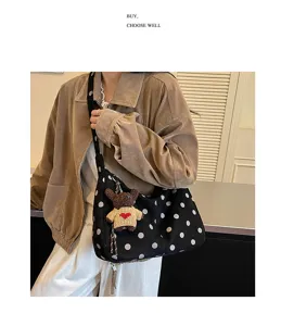 Detailed view of the retro polka dot suede hobo bag with a cute knitted bear pendant.