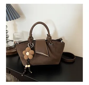 Close-up detail of the vintage brown suede handbag showcasing the cute flower charm texture.
