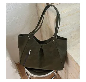 Close-up detail of dark green women leather tote bag with metal zipper and rivet decor scene.