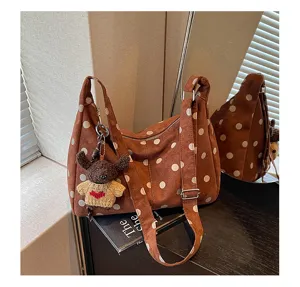 Detail view of brown polka dot suede hobo shoulder bag featuring cute bear charm.