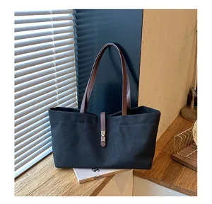 Classic black canvas tote bag with brown leather handles and chic metal lock closure.