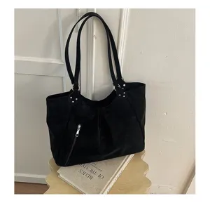 Close-up of black shoulder tote bag detail, featuring double straps and side zipper pocket.