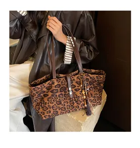 Detalle de un bolso shopper de ante con estampado de leopardo, borla y cierre metálico.
