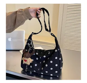 Detail view of black polka dot shoulder bag with cute bear charm for women autumn winter