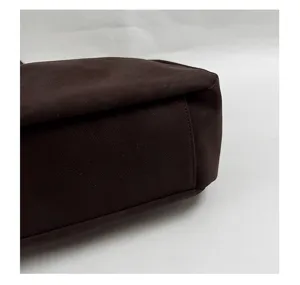 Detail shot of dark brown leather tote bag bottom, featuring smooth texture and neat stitching.