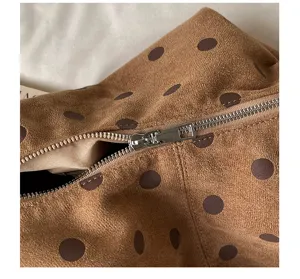 Detail view of brown suede polka dot underarm bag featuring smooth metallic zipper and texture.