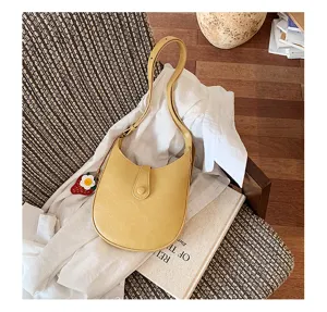 Minimalist yellow PU leather underarm shoulder bag for women, chic saddle bag with cute charm.