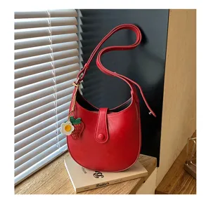 Red leather saddle bag, stylish women shoulder crossbody bag with cute strawberry charm.