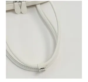 Primer plano del asa del bolso de mujer blanco con botón de presión de metal y correa.