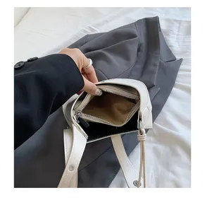 Detailed view of white minimalist leather underarm bag interior structure and zipper pocket.