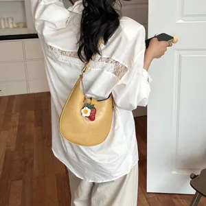Stylish yellow saddle bag for women, chic minimalist hobo shoulder handbag with cute charm.